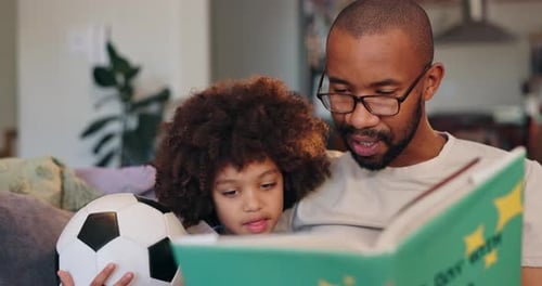 Father Reads Book to Child With Soccer Ball
