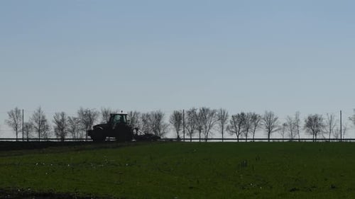 Silhouette eines landwirtschaftlichen Traktors mit Pinne im Feld