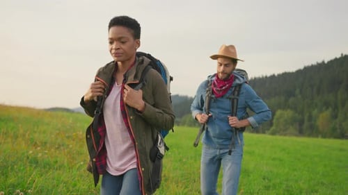Couple Hiking Through Grassy Hills in the Countryside