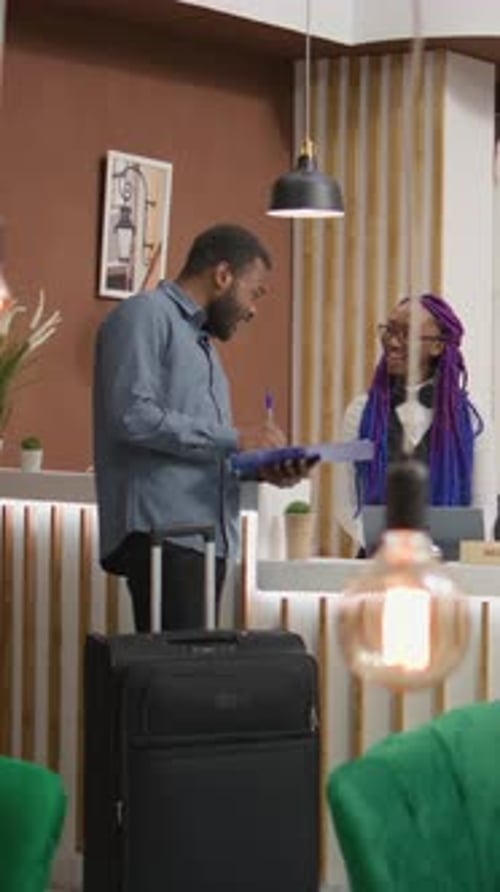 Man Signing Hotel Registration Form at Front Desk