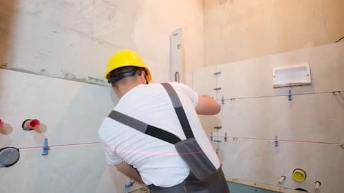 Tiler Installing Tiles with Leveling Instrument