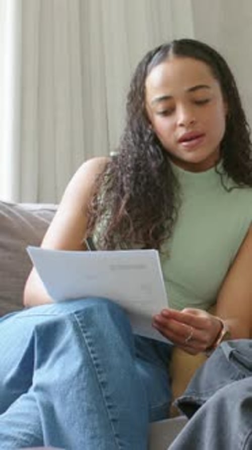 Vertical video: Receiving paper, woman in green top annotating on couch with pen and mug to discuss