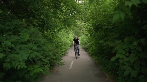 Young Boy Riding Bicycle on Scenic Path Surrounded By Lush Greenery
