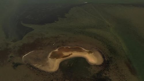 A top-down aerial view over a salt marsh, it is low tide & you can see a sandbar in the waters below