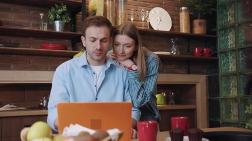 Loving Couple Smiling Looking at Laptop in Kitchen