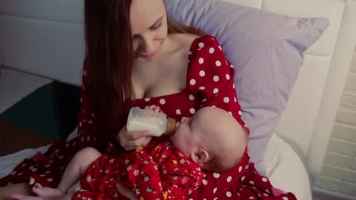 Mother Feeds Infant in Bedroom From Bottle