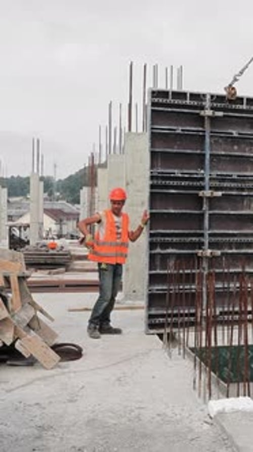 Der Baumeister arbeitet auf der Baustelle und installiert eine große Metallkonstruktion auf dem Dach von