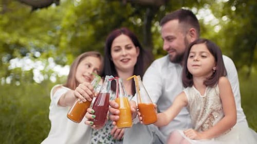 Cheerful Family Enjoying Juice Together Outdoors