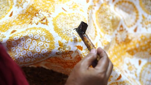 Hand Applying Wax to Fabric with Floral Pattern