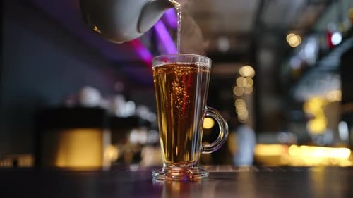 Hot Tea is Poured Into a Glass on the Bar Counter in a Cafe Closeup