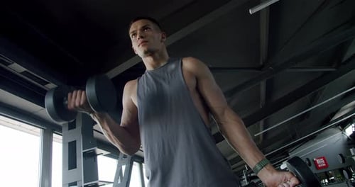 Joven concentrado levantando pesas en un gimnasio moderno