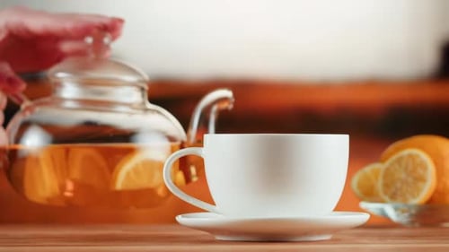 Pouring Lemon Tea into White Cup on Wood