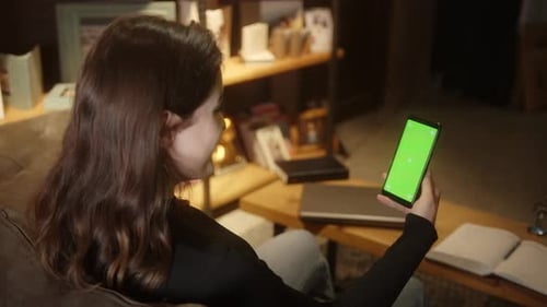 Junge schöne Frau mit braunen Haaren sitzt zu Hause auf dem Sofa
