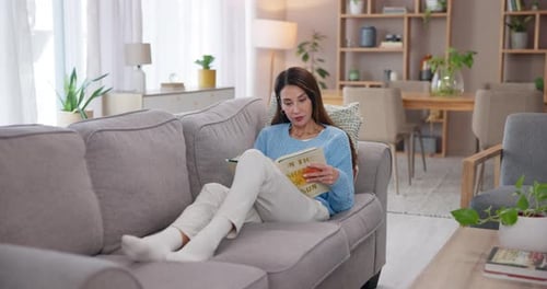 Woman Reading a Book Relaxing on Couch at Home