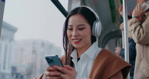Frontal View of Asian Girl Sitting Next to Window in Train or Bus Woman Listening to Music in