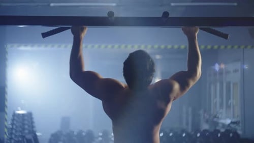 Pumped Up Young Guy Doing Pull Ups in the Gym