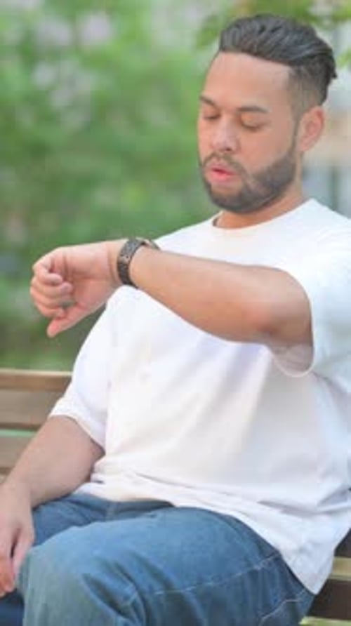 Man Sitting and Checking His Watch in Park
