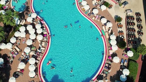Menschen, die sich in einem Sommerresort in der Nähe des Schwimmbades entspannen. Pool mit Sonnenliegen im Luftbild