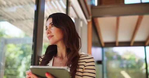 Woman Using Tablet, Looking out Window Indoors