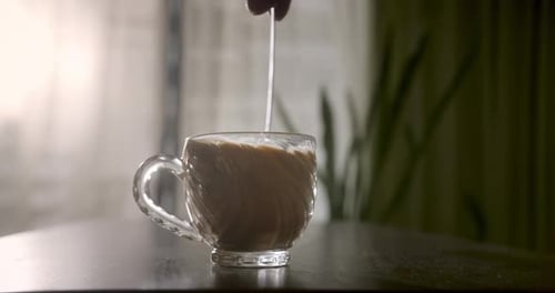 Coffee Mug Stirred Gently with Spoon on Table