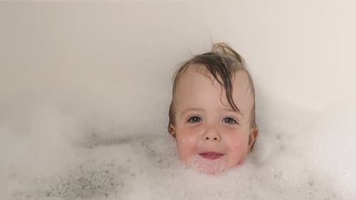 Smiling Child Enjoying a Bubble Bath at Home