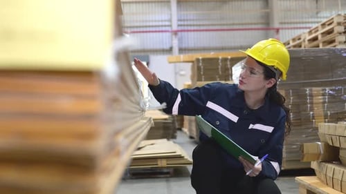 A young female warehouse worker checks and counting cardboard boxes in the warehouse