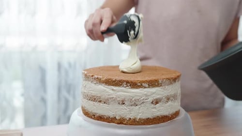 Baker Decorating Layer Cake with White Frosting