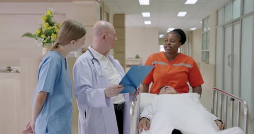 Diverse hospital team discussing unconscious patient’s condition while moving stretcher through