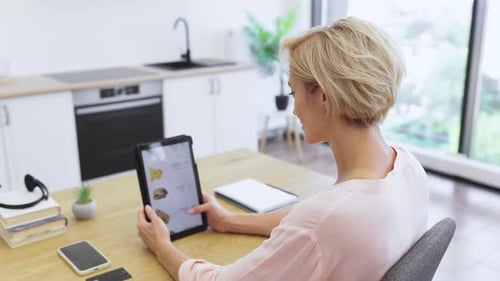 Woman Browsing Online Menu on Tablet in Kitchen