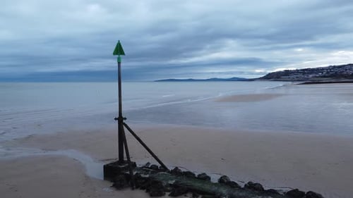Coastal tide marker aerial view low orbit right across moody overcast low tide seaside beach