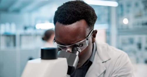 Scientist Concentrated on Microscope Research in Laboratory