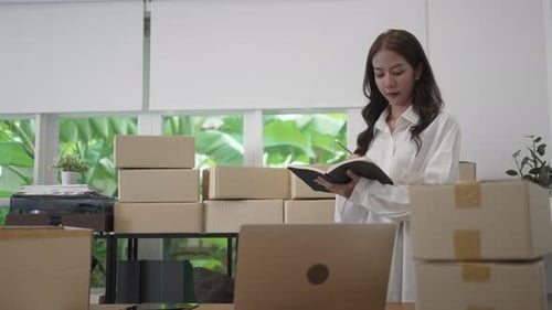 Young female entrepreneur is packing merchandise at home.