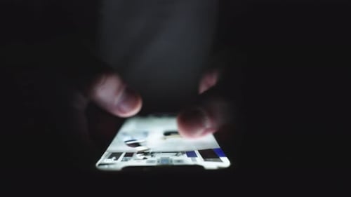 Fingers Scroll Through Glowing Phone In Dark