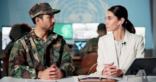 Man in Uniform and Woman Talking at Table