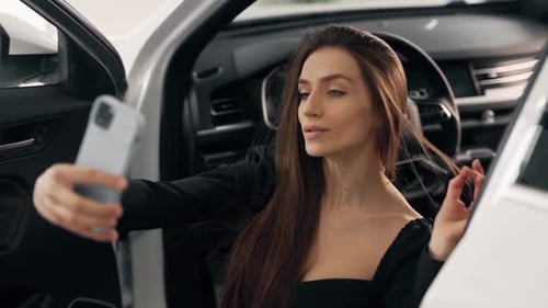 Schönes Mädchen in einem sexy Anzug macht ein Selfie, wenn sie in einem neuen Auto sitzt