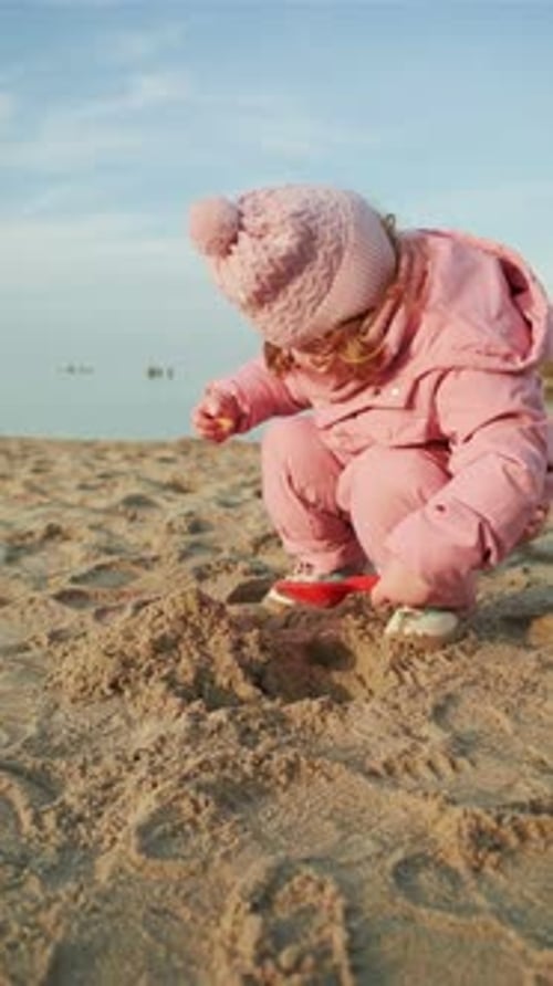 Child Girl Wearing Warm Winter Clothes Playing with Sand on Beach Toddler Using Pink Toy Shovel