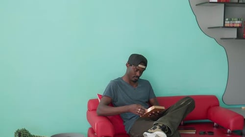 Student Sitting On Couch Reading Book In Relaxed Setting