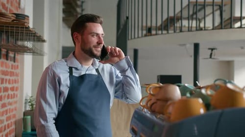 Caucasian Man Waiter Bartender Barista Staff Talk on Mobile Phone Behind Cafeteria Counter Remote