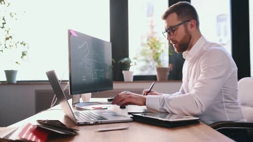 Designer Working on Tablet and Laptop in Office