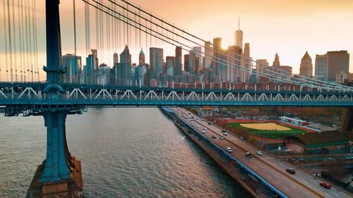 Rising to the top of the Manhattan Bridge in New York. Sun sets behind the skyscrapers skyline.