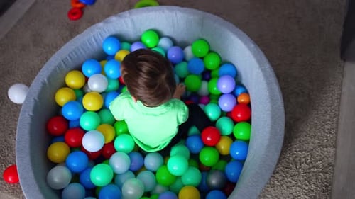 Dark-haired toddler boy sitting in the dry pool.