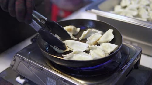 Street vendor is frying jiaozi in a pan