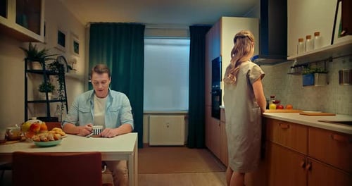 Man Drinking Coffee, Woman Preparing Food Indoors