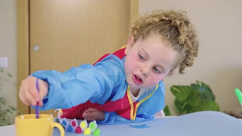 Cute Child Dipping Brush in Water While Painting