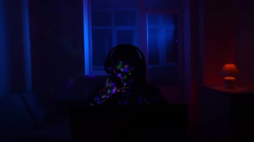 Person with Headphones in a Dark Room at Night