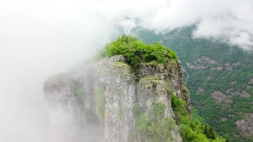 Voando através das nuvens acima da floresta montanhosa com vista aérea superior da névoa matinal