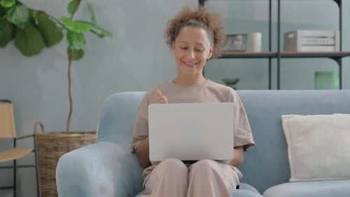 Woman on Video Call Waving from Couch