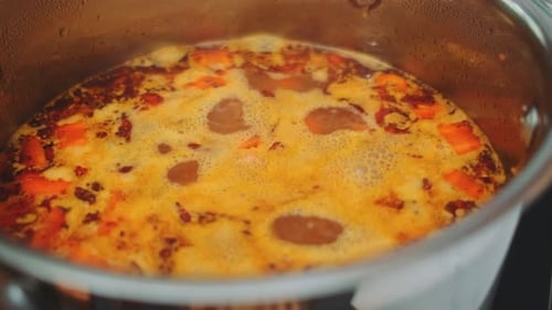 Stirring a Boiling Vegetable Soup with a Spoon