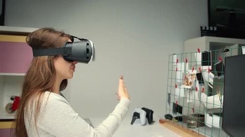 Young woman office worker uses virtual reality glasses in office interior