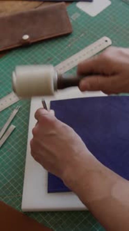 Unrecognizable Hands Making Stitching Holes in Piece of Blue Colored Leather